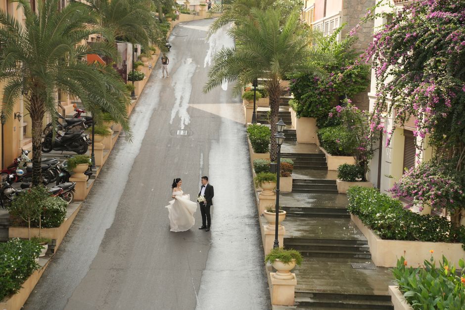 Aerial view of newlyweds on a charming city street lined with palm trees and flowers.