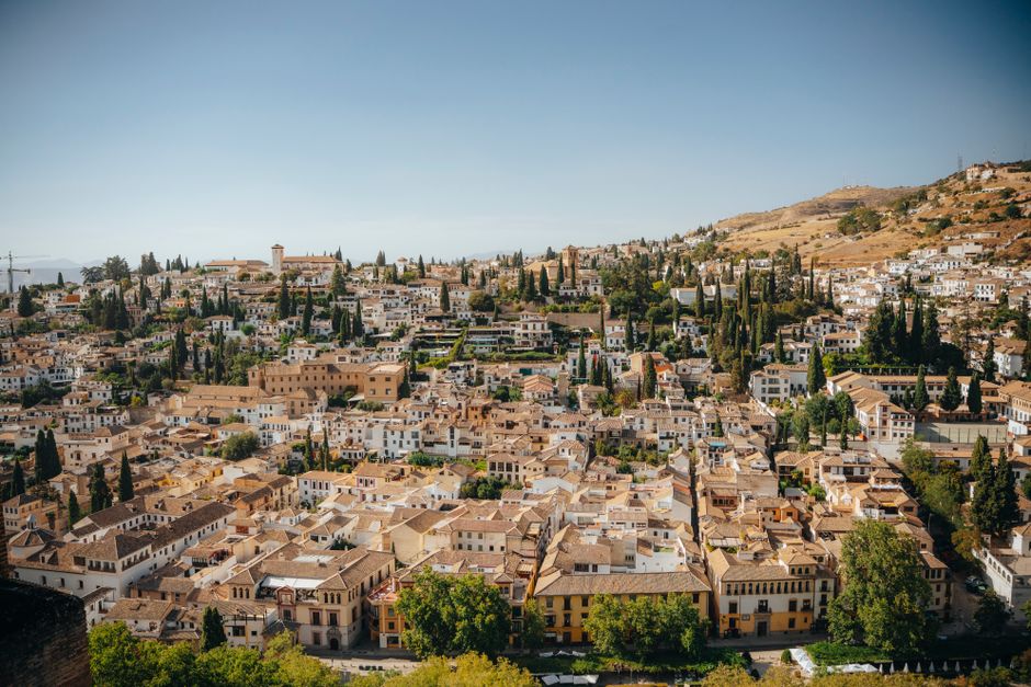 Aerial view of Granada's historic neighbourhoods with a backdrop of hills and clear skies.