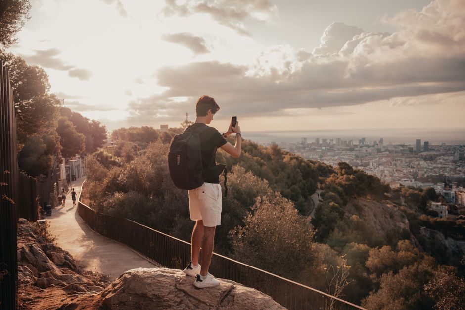 A traveler takes photos of Barcelona from a scenic overlook at sunset.