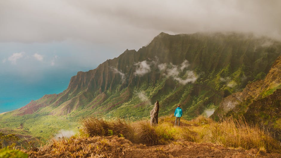 Stunning landscape of Napali coast with a hiker enjoying the breathtaking view.