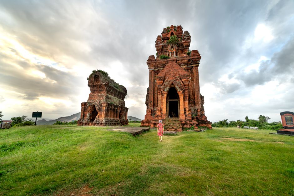 Explore the historic Cham temple ruins set in a lush landscape under an overcast sky.