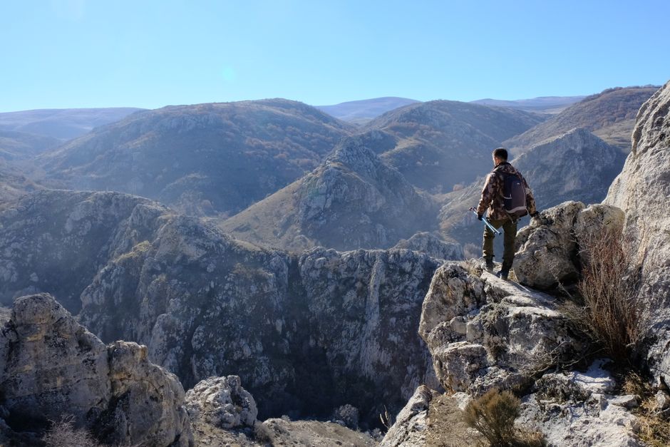 A lone hiker surveys the breathtaking mountainous landscape in Türkiye, evoking a sense of adventure and serenity.