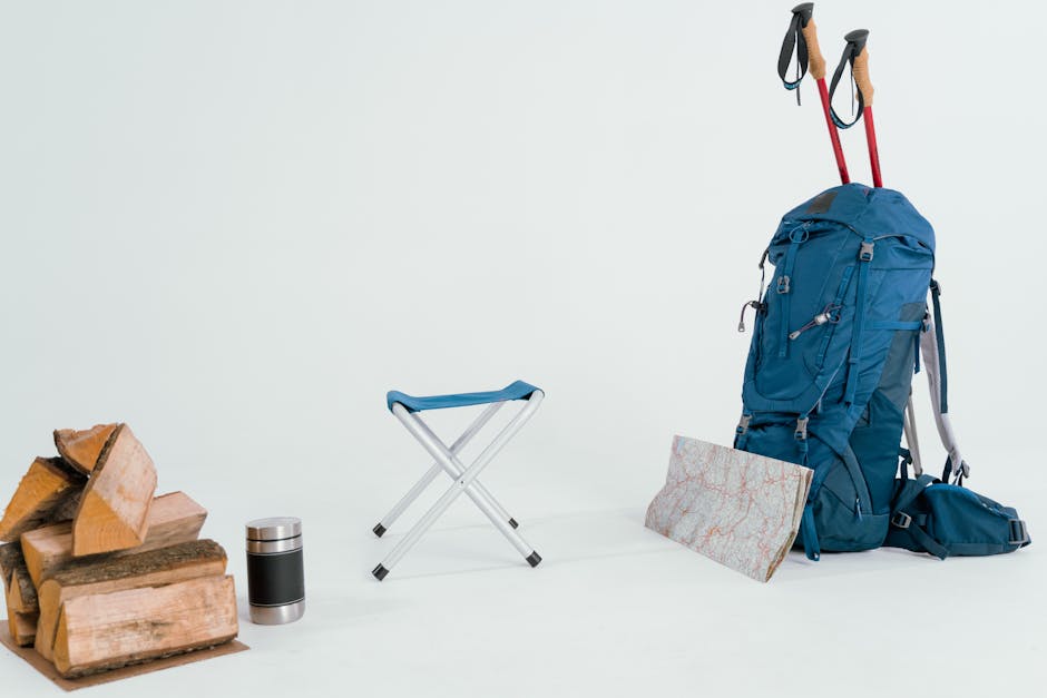 A collection of hiking gear including a backpack, map, and chair for winter expeditions.