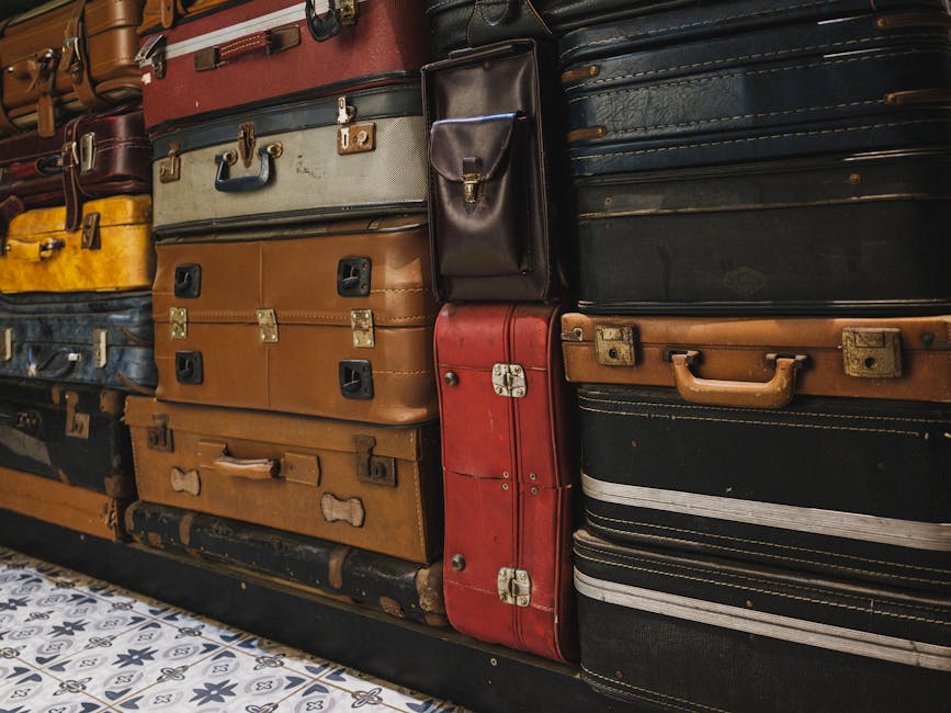 A collection of stacked vintage suitcases showcasing classic styles in an indoor setting.
