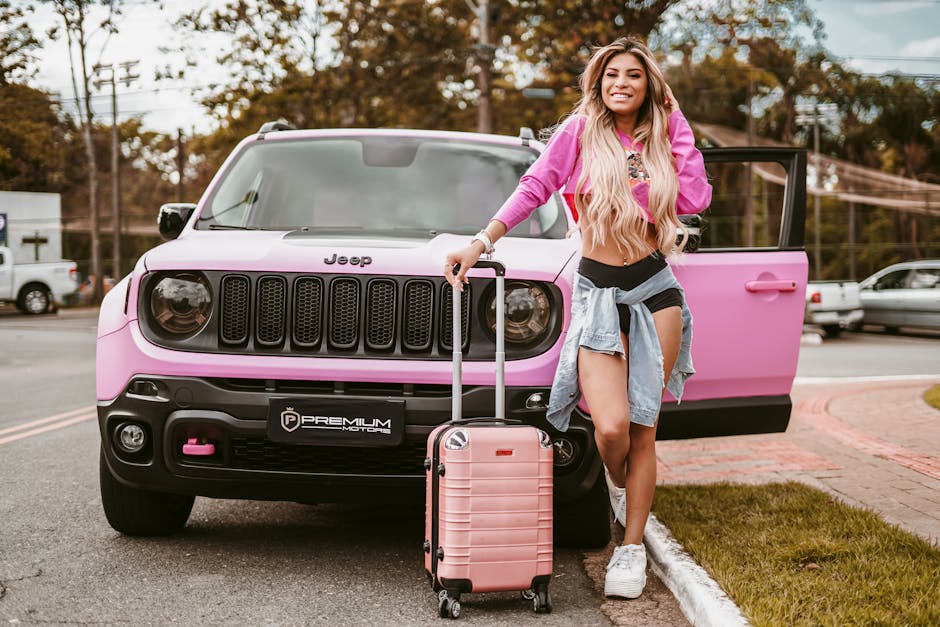 Fashionable young woman with pink top and suitcase standing by a pink SUV outdoors.