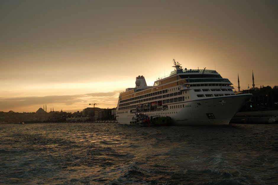 A majestic cruise ship docked at Istanbul's port during a stunning sunset.