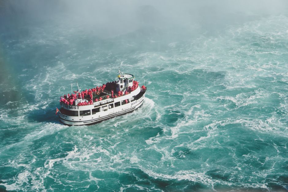 Aerial view of Maid of the Mist tourist boat amidst turbulent waters at Niagara Falls.