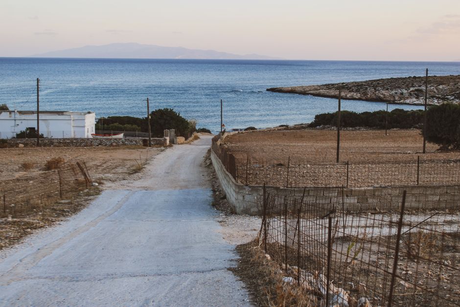 Scenic dirt road leading to a tranquil sea view, ideal for peaceful travel imagery.