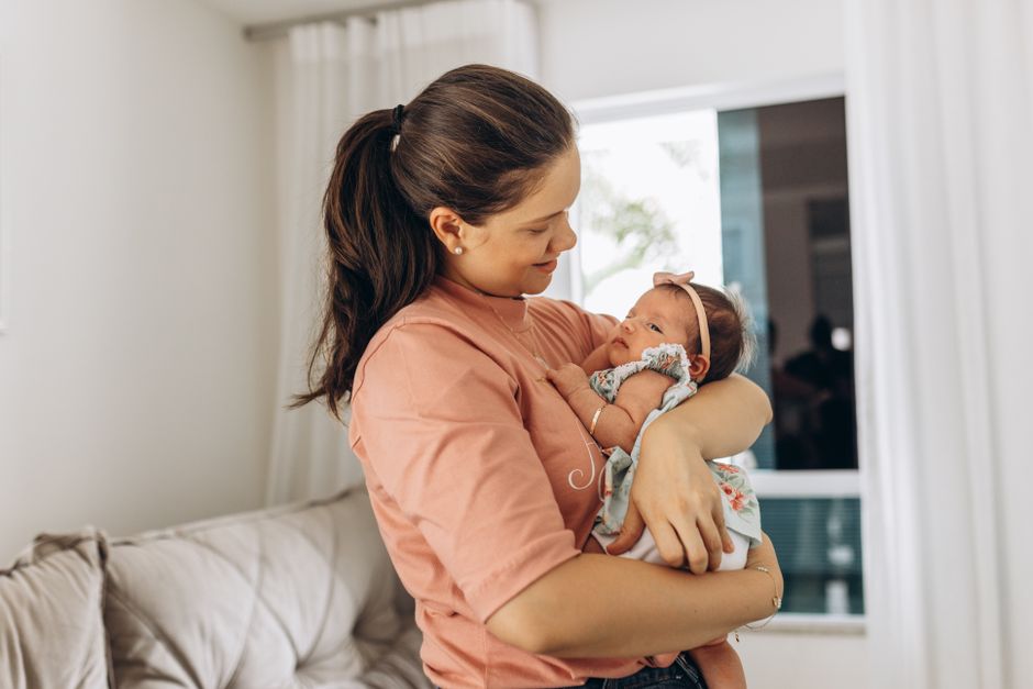 A mother lovingly holds her newborn in a serene living room setting.