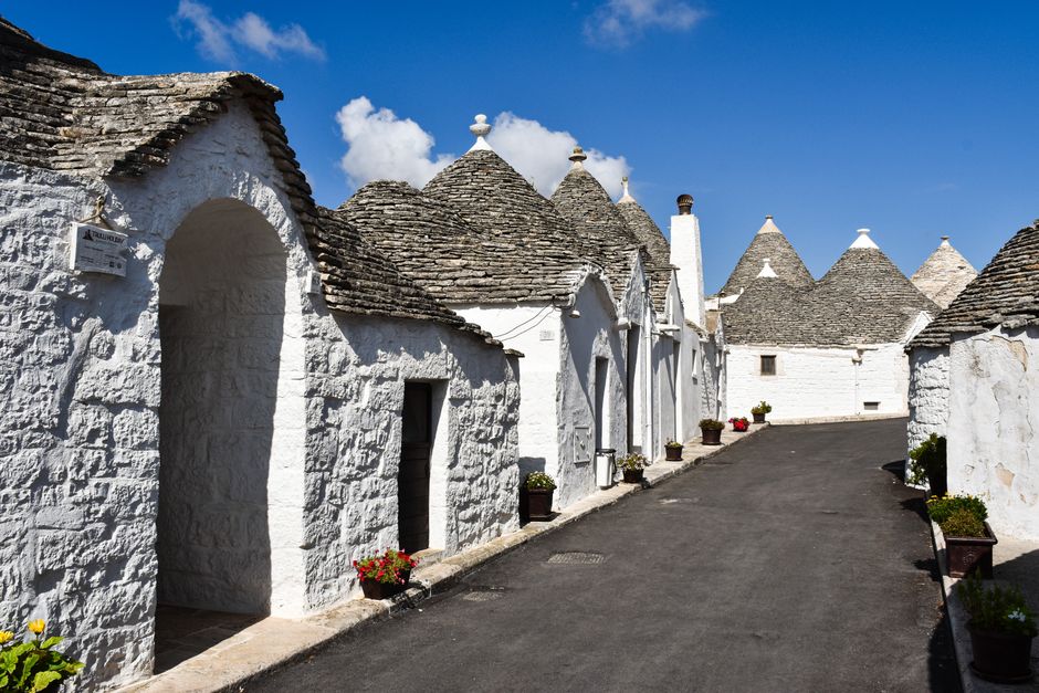 Picturesque street view of traditional Trulli houses with conical roofs in Alberobello, Apulia, Italy.
