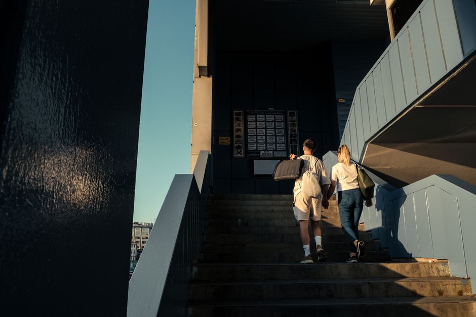 A man and woman holding hands while ascending outdoor stairs in a city.