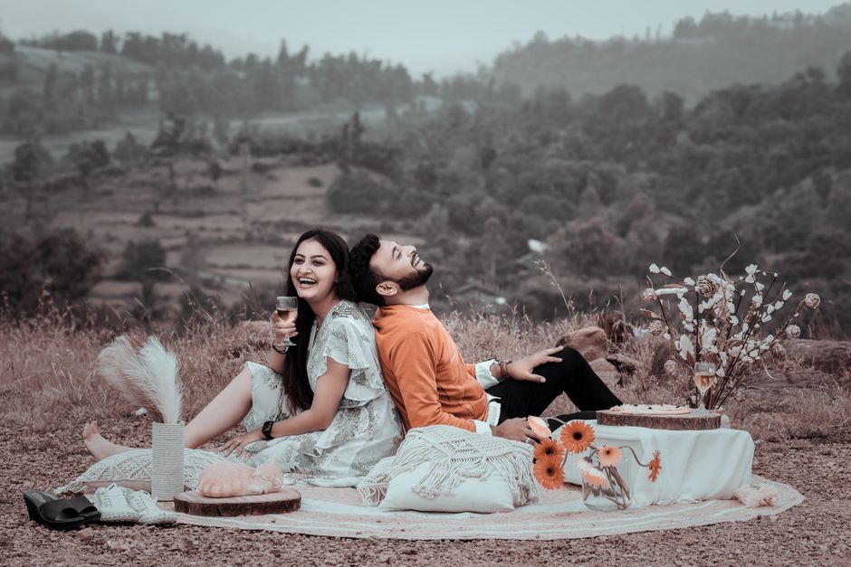 A couple enjoying a romantic picnic outdoors, surrounded by nature and laughter.