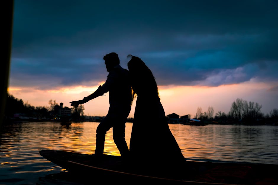 A couple enjoys a romantic boat ride at sunset, captured in silhouette.