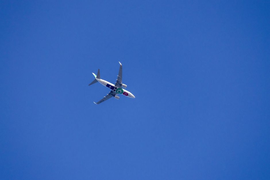 A commercial airplane flying high against a clear blue sky, showcasing air travel.