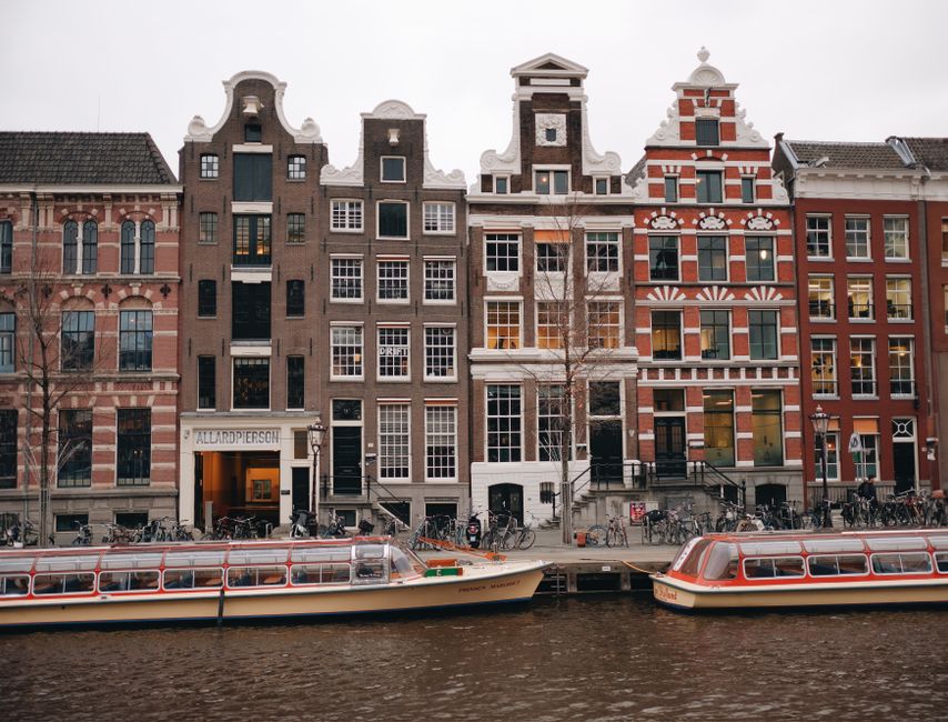 Charming view of Amsterdam's iconic canal and rowhouses with tour boats.