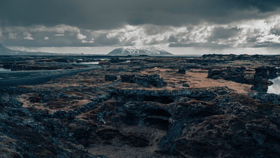 Explore Iceland's stunning volcanic terrain and distant mountains under moody skies.