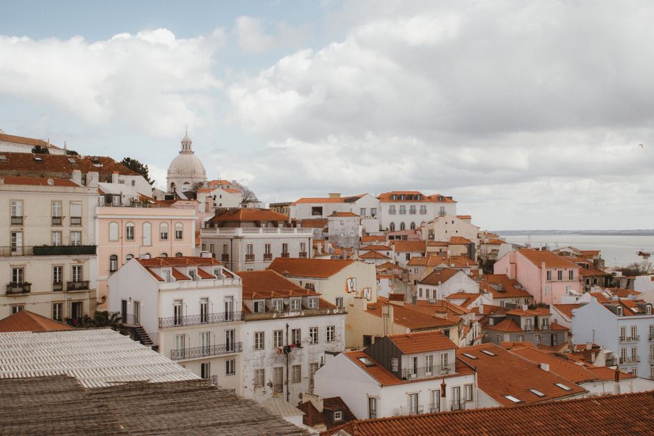 Beautiful view of Lisbon's iconic red rooftops and dome under a cloudy sky.