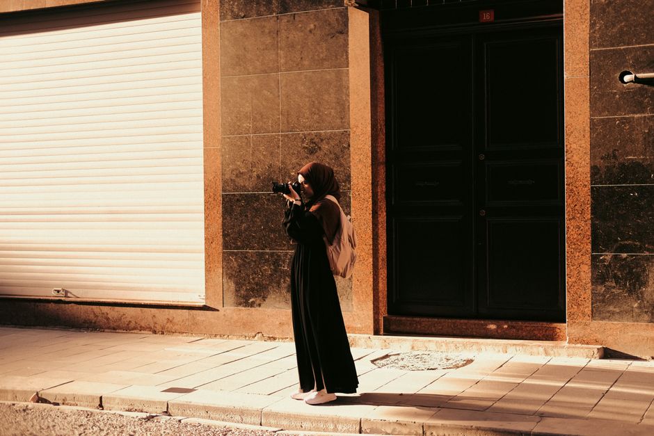 Female photographer in urban setting with camera on sunny day.