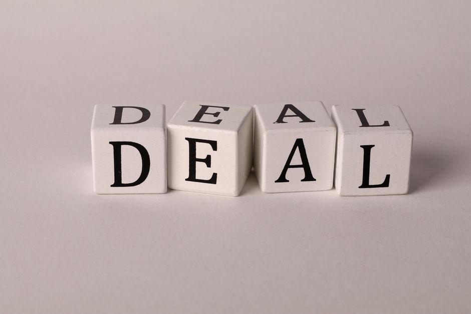 Close-up of white cubes with black letters spelling DEAL on a plain background.