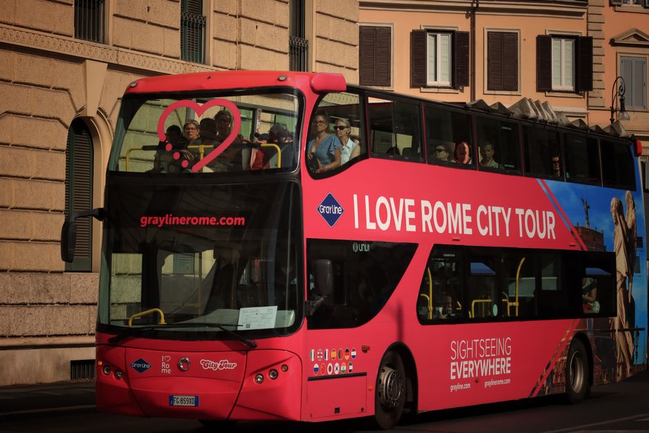 Double-decker bus for sightseeing in Rome with tourists enjoying the city views.