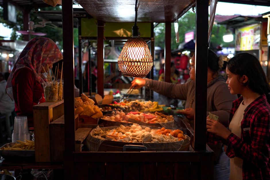 A vibrant street food market scene captured in Denpasar, Bali, showcasing traditional market activities.