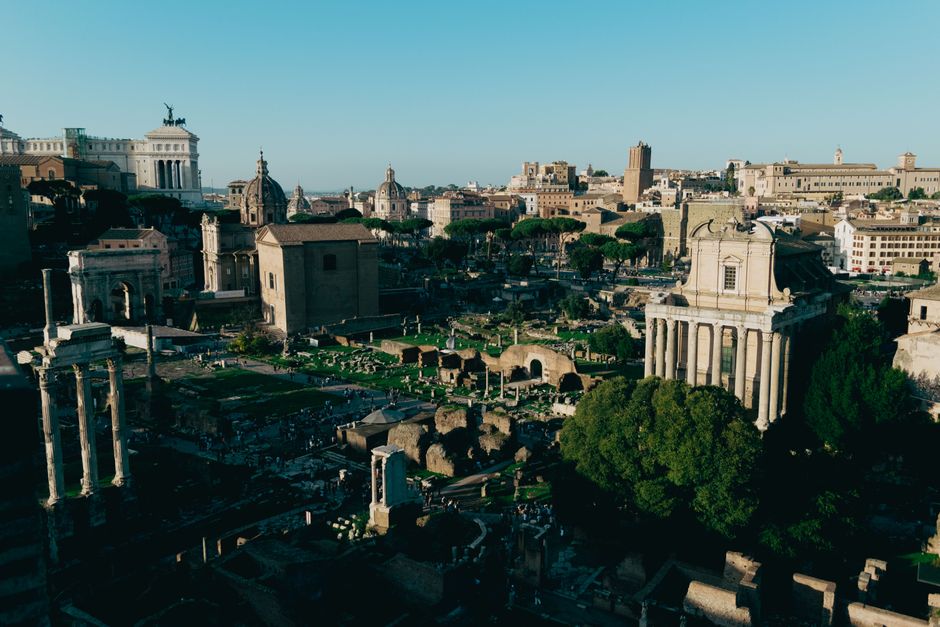 Aerial view of the historic Roman Forum showcasing ancient ruins against a clear sky in Rome, Italy.