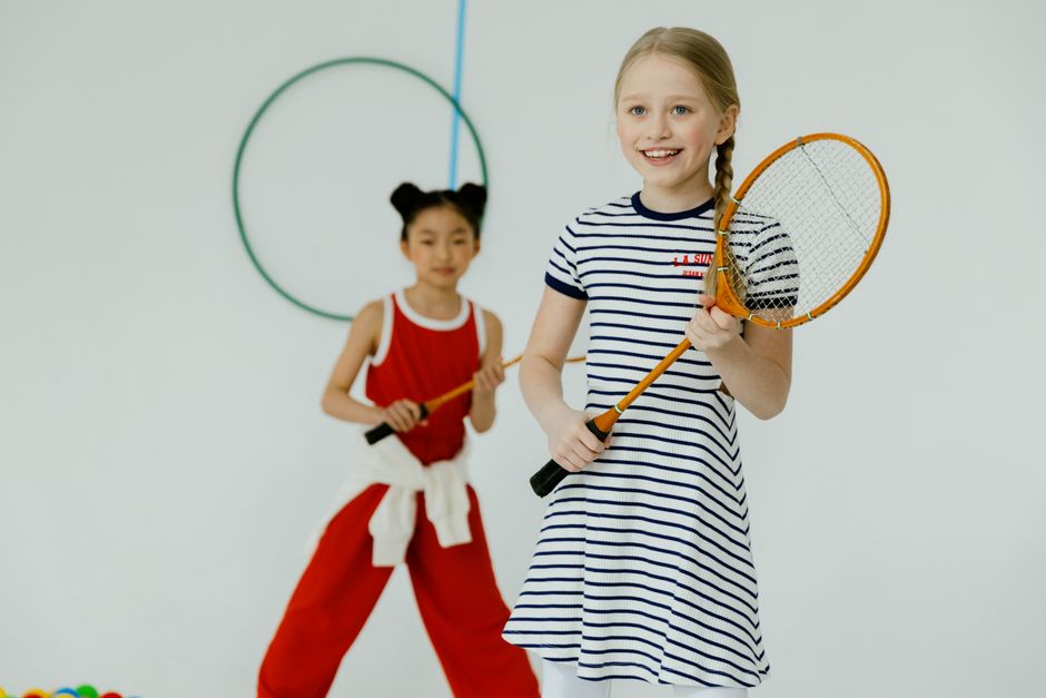 Two children enjoy indoor racquet games with smiles and energy.