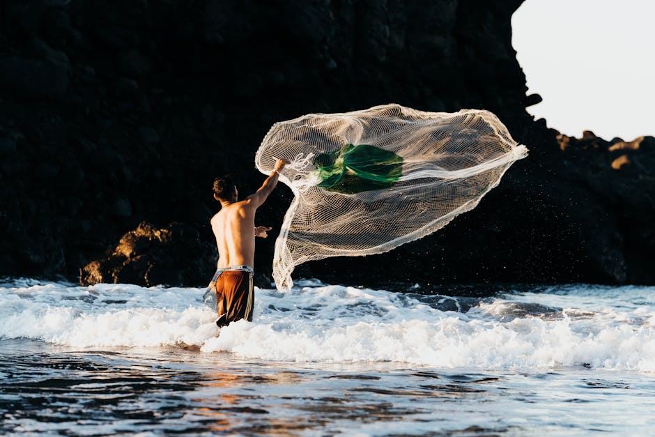 A fisherman skillfully casting a net in the waves of El Tunco Beach, El Salvador.