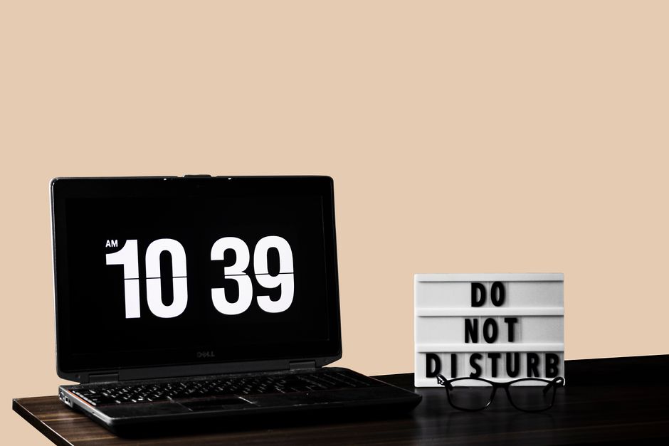 Modern workspace featuring a laptop and 'Do Not Disturb' sign on a wooden desk.