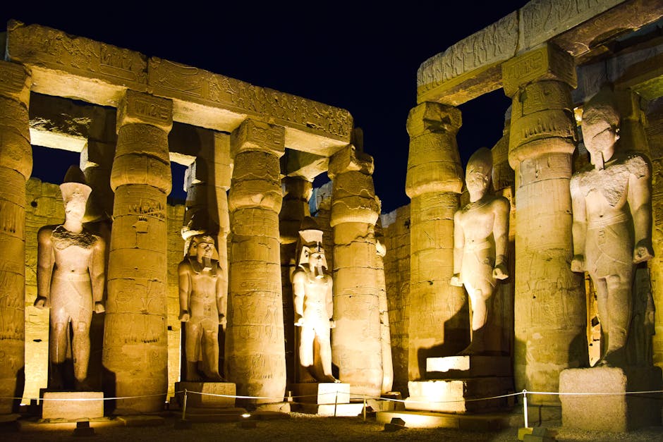 Night view of illuminated ancient statues at Luxor Temple, showcasing historical Egyptian architecture.