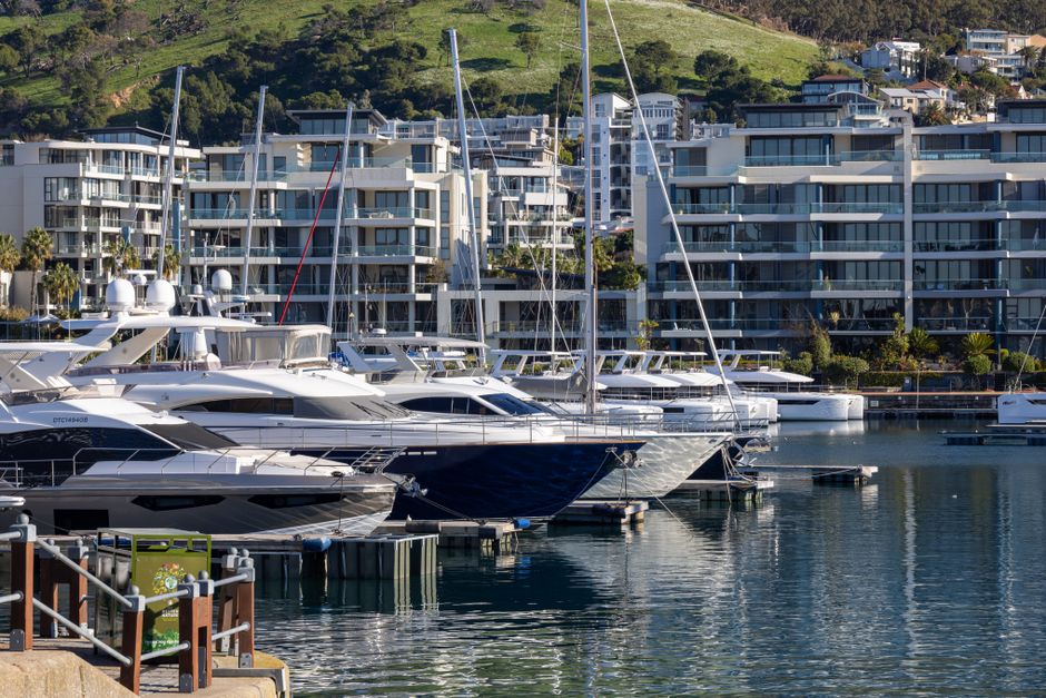 A scenic view of luxury yachts moored at a modern marina with apartments in the background.