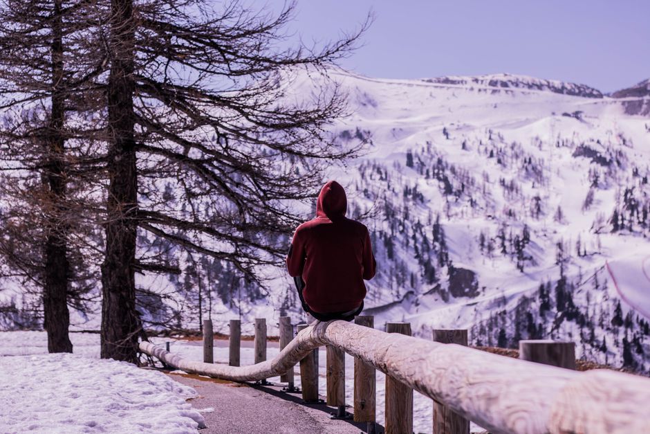 A solitary figure in a hoodie enjoys the serene snowy landscape in the Italian mountains.